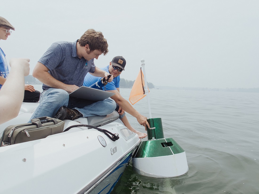 Jed Harvey, Lilly Center research technician, and Stephen Foy, of the field research team, install the buoy on Lake Wawasee. Photo Provided.