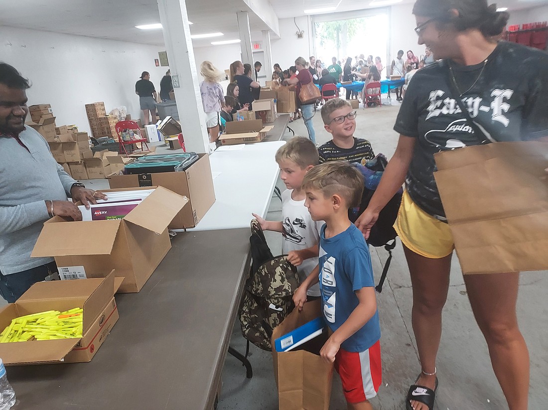 Venkat Roa (L) helps Meghan McDaniel and her children Axel and Jax Lewallen and Rohnan Timmons get school supplies during Tools for School Wednesday at the Kosciusko County fairgrounds. Photo by Jackie Gorski, Times-Union