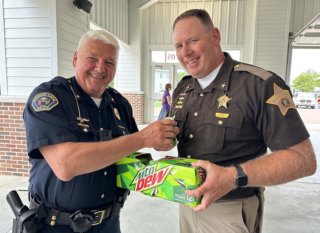 Winona Lake Police Chief Joe Hawn (L) offers Kosciusko County Sheriff Jim Smith (R) a Mountain Dew during Monday’s “Jacked Up On Mountain Dew, Send Them Back To School Special” cookout lunch at Miller Sunset Pavilion in Winona Lake Monday. Photo by David Slone, Times-Union