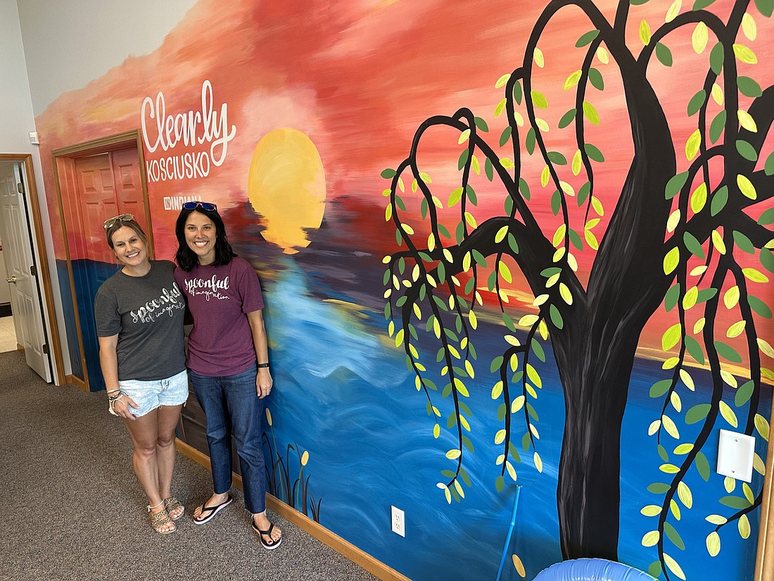 Artists Erica Deuel (R) and Beth Williman (L), of Spoonful of Imagination, pose with the mural they created for the Kosciusko County Convention & Visitors Bureau Visitor Center. Photo by David Slone, Times-Union