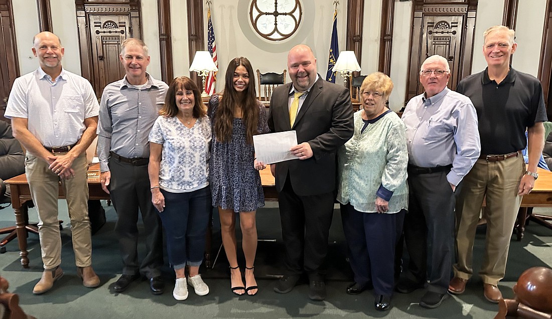 A from the Association of Indiana Counties (AIC) and Nationwide Retirement Solutions was presented to Talia Holder Tuesday at the Kosciusko County Commissioners meeting. Pictured (L to R) are Cary Groninger, commissioner; Bill Holder, county GIS director and Talia’s father; Joy Holder, mother; Talia Holder; Patrick Burkhart, Nationwide; Sue Ann Mitchell, county councilwoman and AIC second vice president; Bob Conley and Brad Jackson, county commissioners. Photo by David Slone, Times-Union