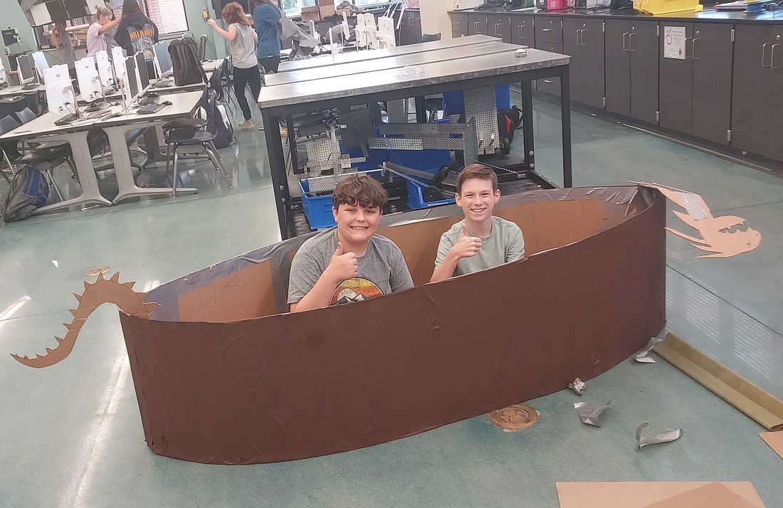 Jacob Warren (L) and Brodie Biggs (R) work on their cardboard boat for Saturday’s regatta during Canal Days. Photo by Jackie Gorski, Times-Union