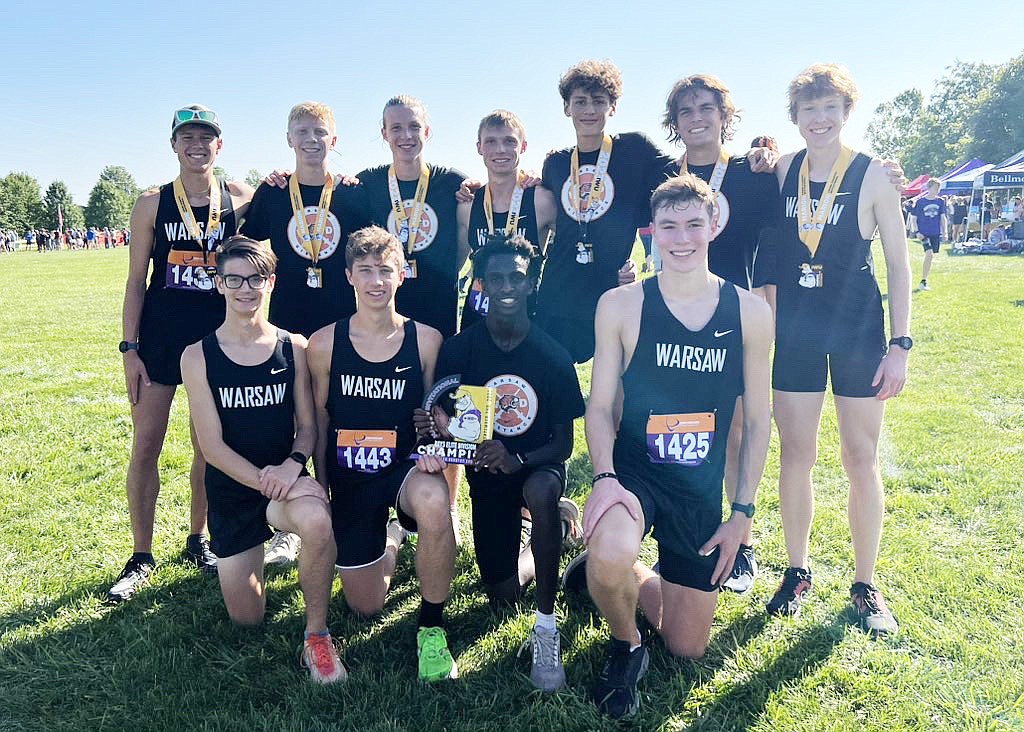 The Warsaw boys cross country team celebrates with its newest piece of hardware after winning the Marion Invitational on Saturday. Photo provided by Warsaw Tigers