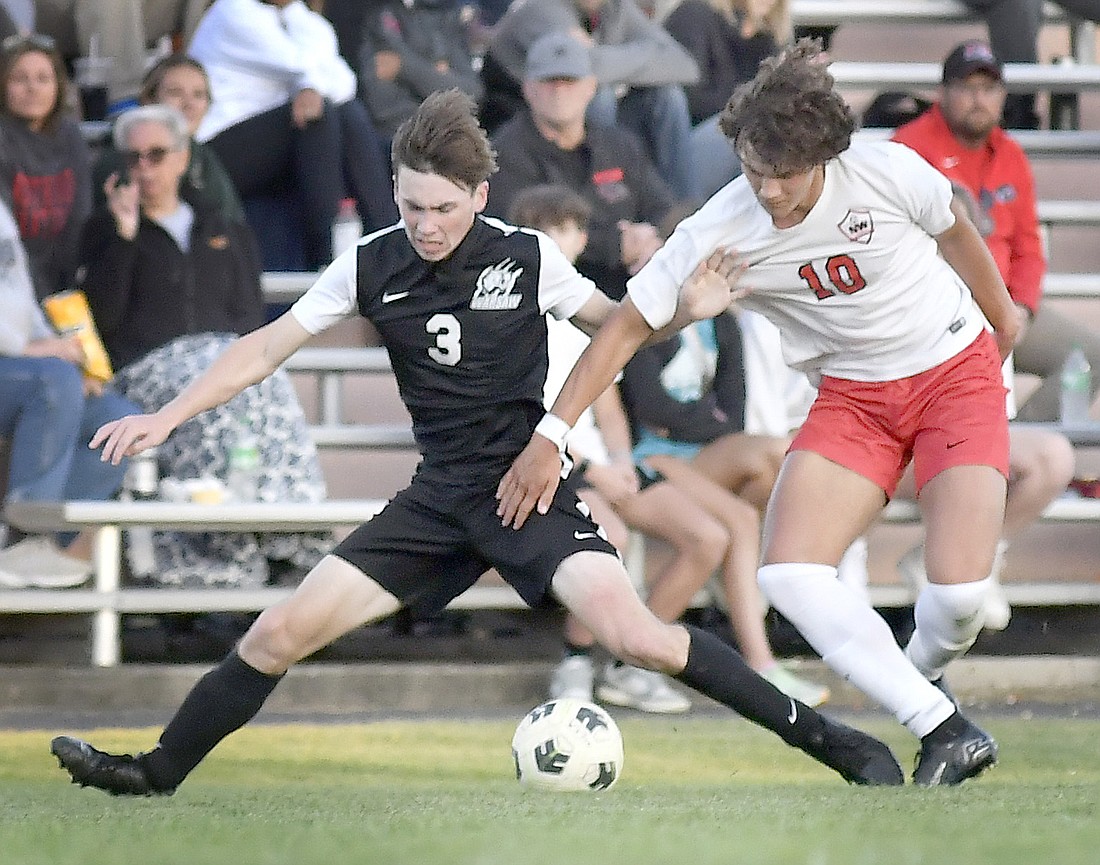 Warsaw senior Talan Asay does the splits to control the ball while fending off NorthWood's Dominic De Freitas. Photo by Gary Nieter