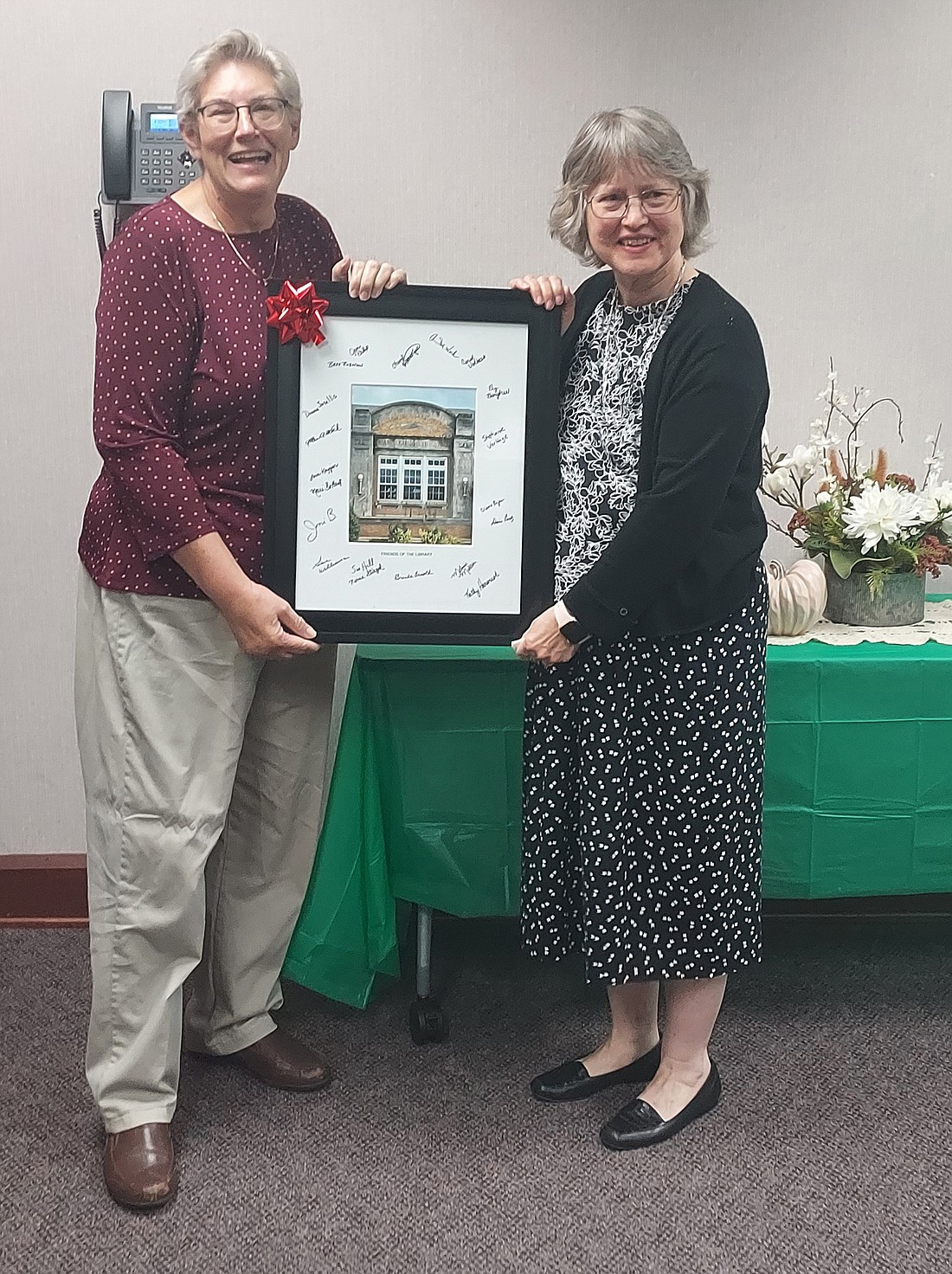 Ann Zydek, Warsaw Community Public Library director, was presented with a signed framed picture of the library during an open house celebrating her retirement Tuesday. Pictured (L to R) are Ann Werk, Friends of the Library president; and Zydek. Photo by Jackie Gorski, Times-Union