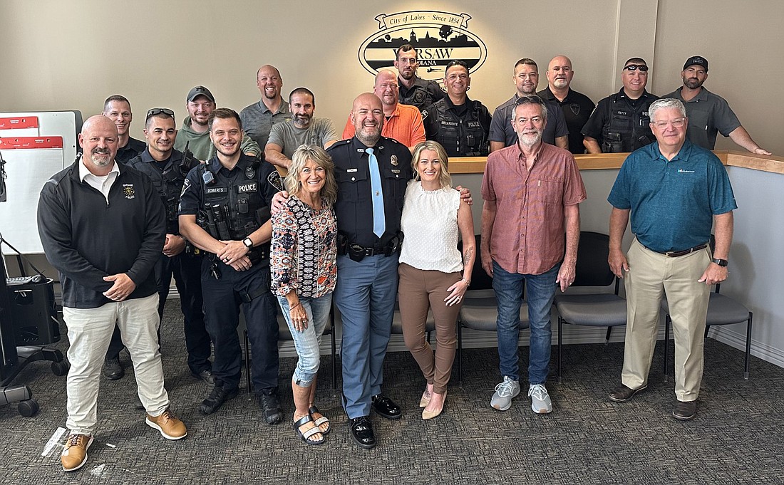 Warsaw Police Department officer Chris Francis (C) poses for a group photo with members of the WPD, Mayor Joe Thallemer (front row, R); his mom, Lisa Strombeck (to his right); wife, LeAnne Francis (to his left); and father, Mark Francis (second from right, first row), after taking the ceremonial oath of office Friday. Photo by David Slone, Times-Union