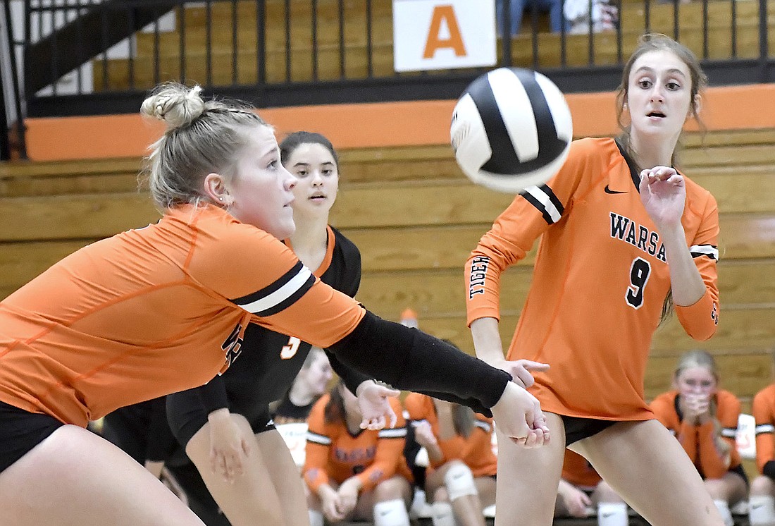 Warsaw senior Claire Reichenbach makes a play on the ball under the watch of teammates Ellie Hepler and Leah Henderson. Photo by Gary Nieter