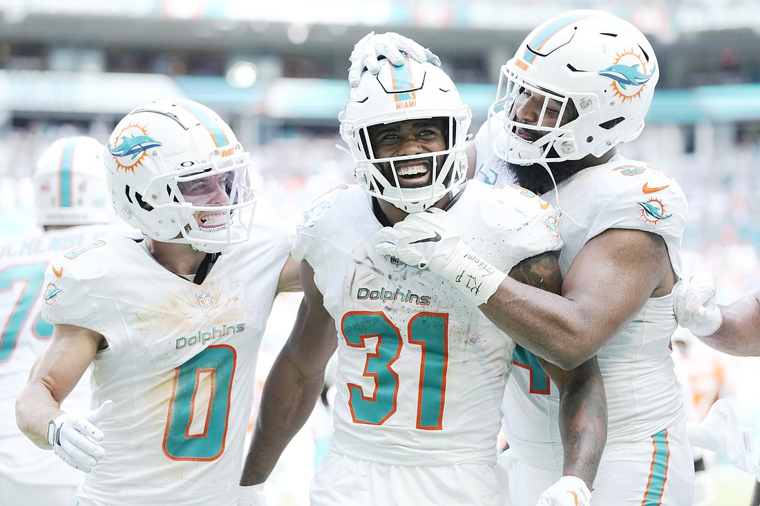 Miami Dolphins running back Raheem Mostert (31) is congratulated by wide receiver Braxton Berrios (0) and defensive tackle Christian Wilkins (94) after scoring a touchdown during the second half of an NFL football game against the Denver Broncos, Sunday, Sept. 24, 2023, in Miami Gardens, Fla. (AP Photo/Rebecca Blackwell)