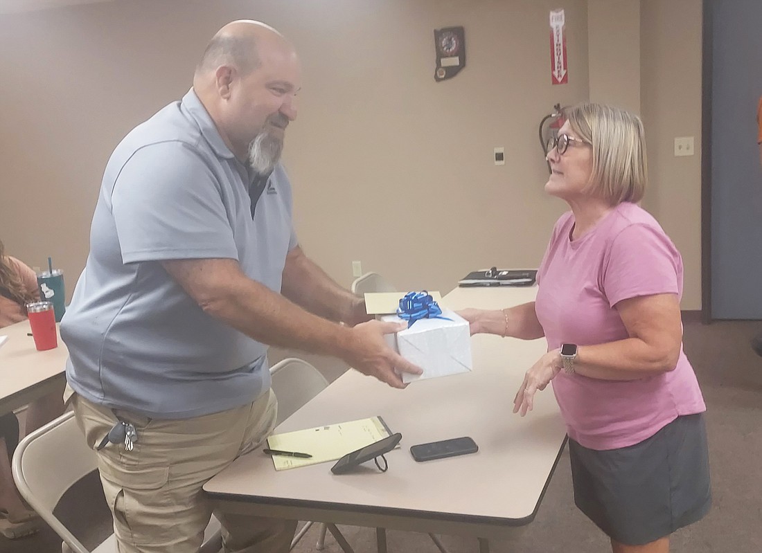 Mentone Town Council President Jill Gross (R) presents Town Marshal Jim Eads (L) with a gift from town employees. Eads will retire effective Oct. 30. Photo by Jackie Gorski, Times-Union