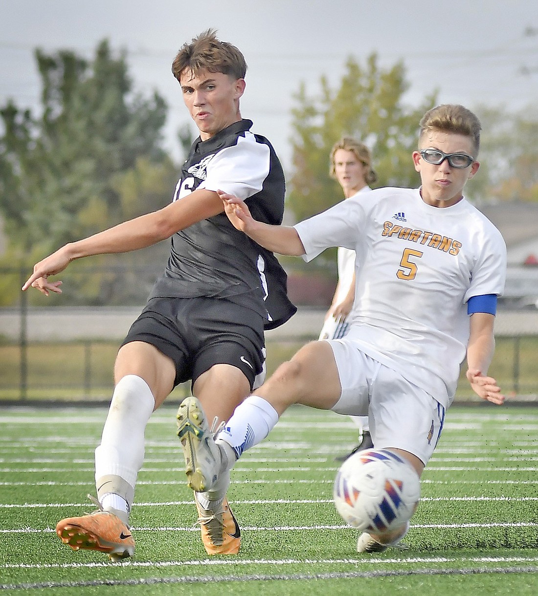 Junior Tanner Reynolds of Warsaw takes a shot on goal as Jacob Cohen of Homestead slides in to defend. Photo by Gary Nieter