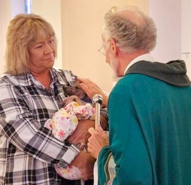 Michael Basden (R), a former longtime rector with St. Anne's Episcopal Church in Warsaw, blesses a rescue dog named Bobby Sunday during a pet blessing ceremony at the church. On the left, Animal Welfare League of Kosciusko County Executive Director Tonya Blanchard holds Bobby, who was rescued from a home in Cromwell Friday. Photo by Dan Spalding, News Now Warsaw