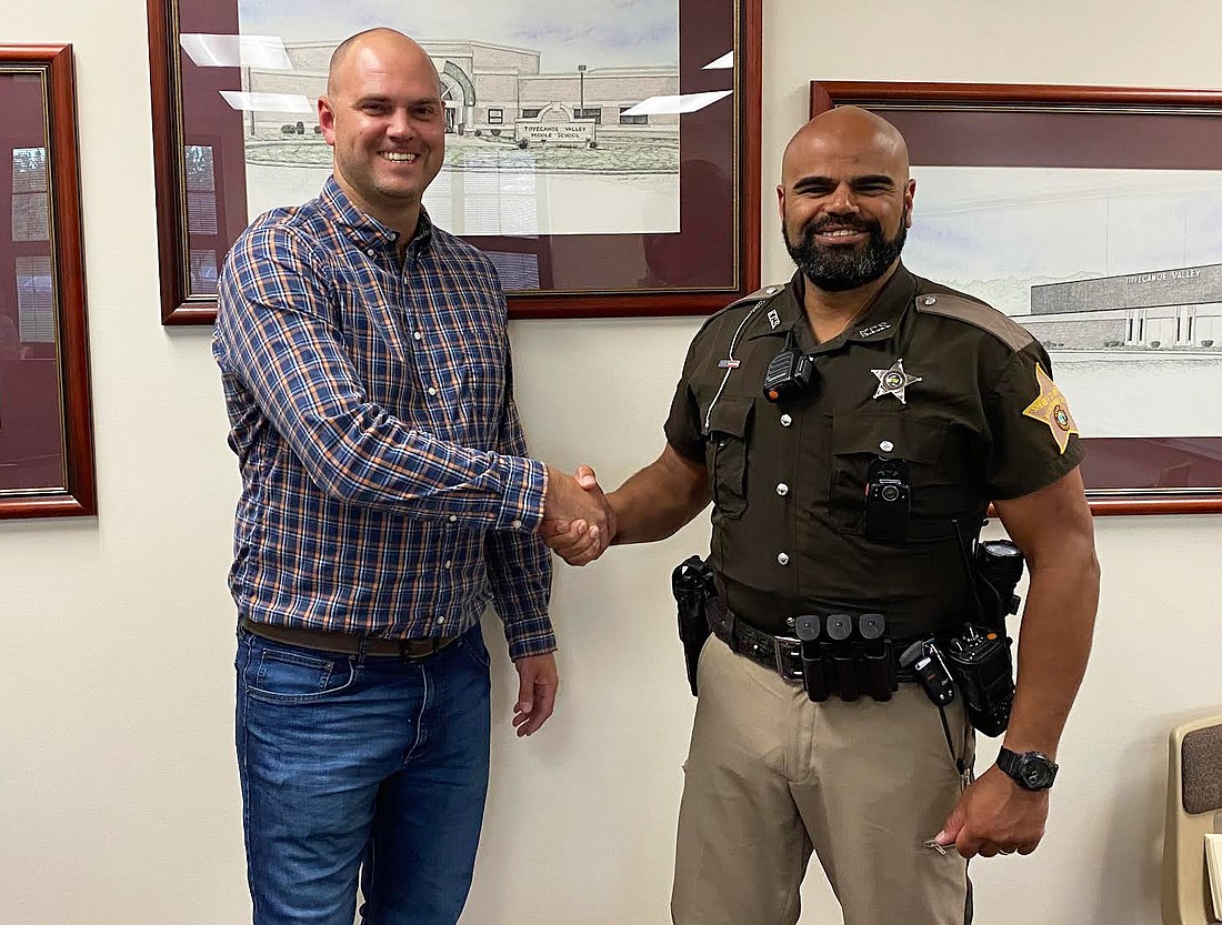 Tippecanoe Valley School Board President David Lash (L) shakes new Tippecanoe Valley School Corp. school resource officer Shaun Mudd’s hand after the board’s regular meeting on Monday at Mentone Elementary School. Photo by Leah Sander, InkFreeNews