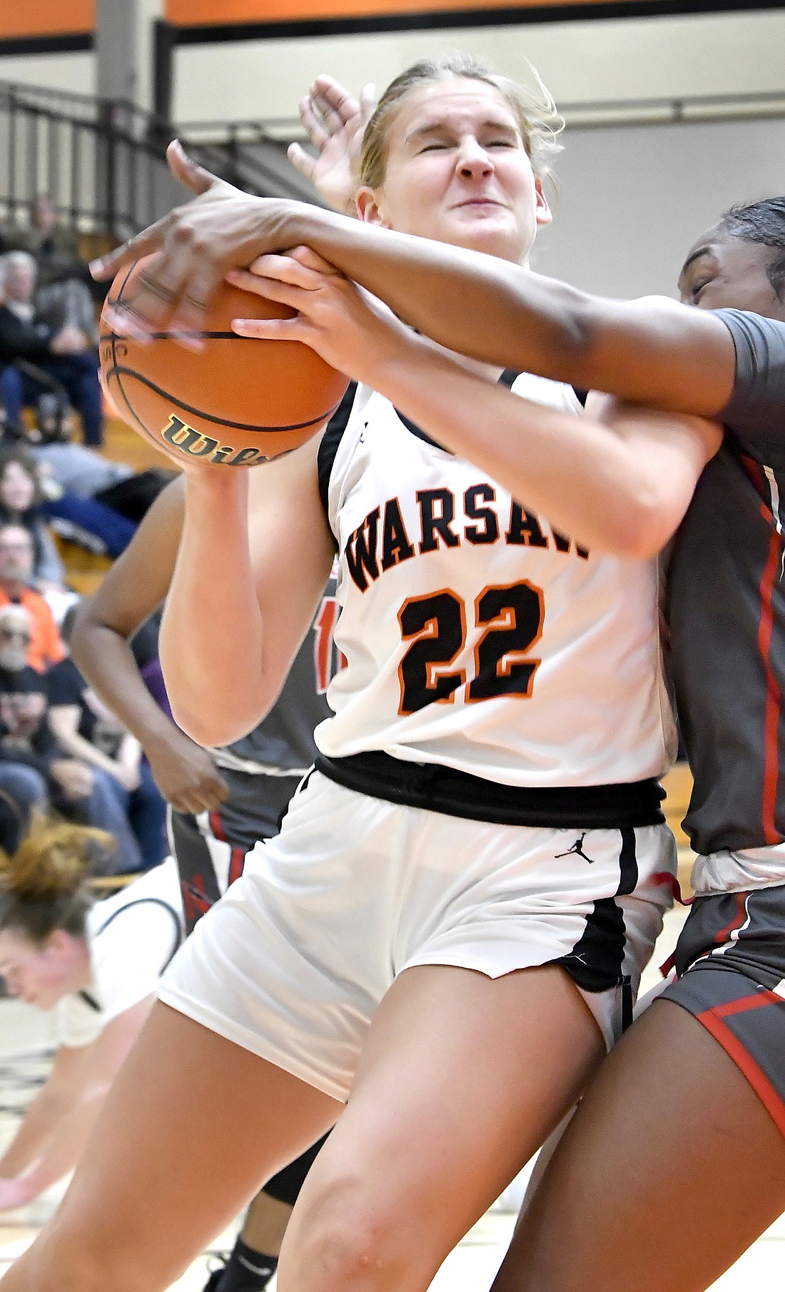 Junior Brooke Winchester of Warsaw takes a hard foul while working under the basket in the first quarter. Photo by Gary Nieter