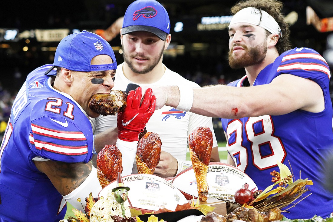 Buffalo Bills safety Jordan Poyer (21), quarterback Josh Allen (17), and tight end Dawson Knox (88) eat a Thanksgiving turkey after an NFL football game against the New Orleans Saints, Thursday, Nov. 25, 2021, in New Orleans. (AP Photo/Tyler Kaufman, File)