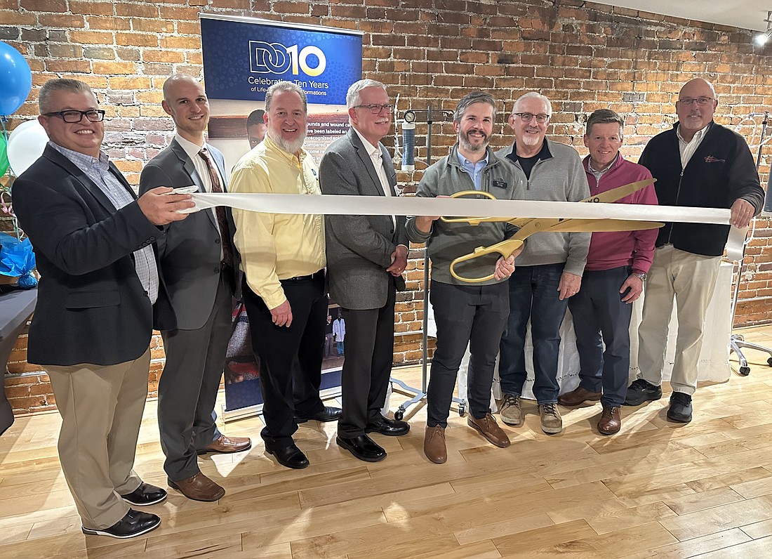 Design Outreach celebrated its Warsaw office in the Kosciusko Economic Development Corporation Downtown Business Studio Tuesday with a ribbon-cutting ceremony with the Kosciusko Chamber of Commerce. Pictured (L to R) are Rob Parker, Chamber president and CEO; Thomas Holton,Design Outreach board member and engineer; Michael Cook, Design Outreach R&D partnerships director; Mark Heldreth, Design Outreach medical fellow; Abraham Wright, Design Outreach chief technology officer; Dean Jessup, Design Outreach board chairman; Bob Vitoux, OrthoWorx CEO; and Scott Wiley, Chamber member relations manager. Photo by David Slone, Times-Union