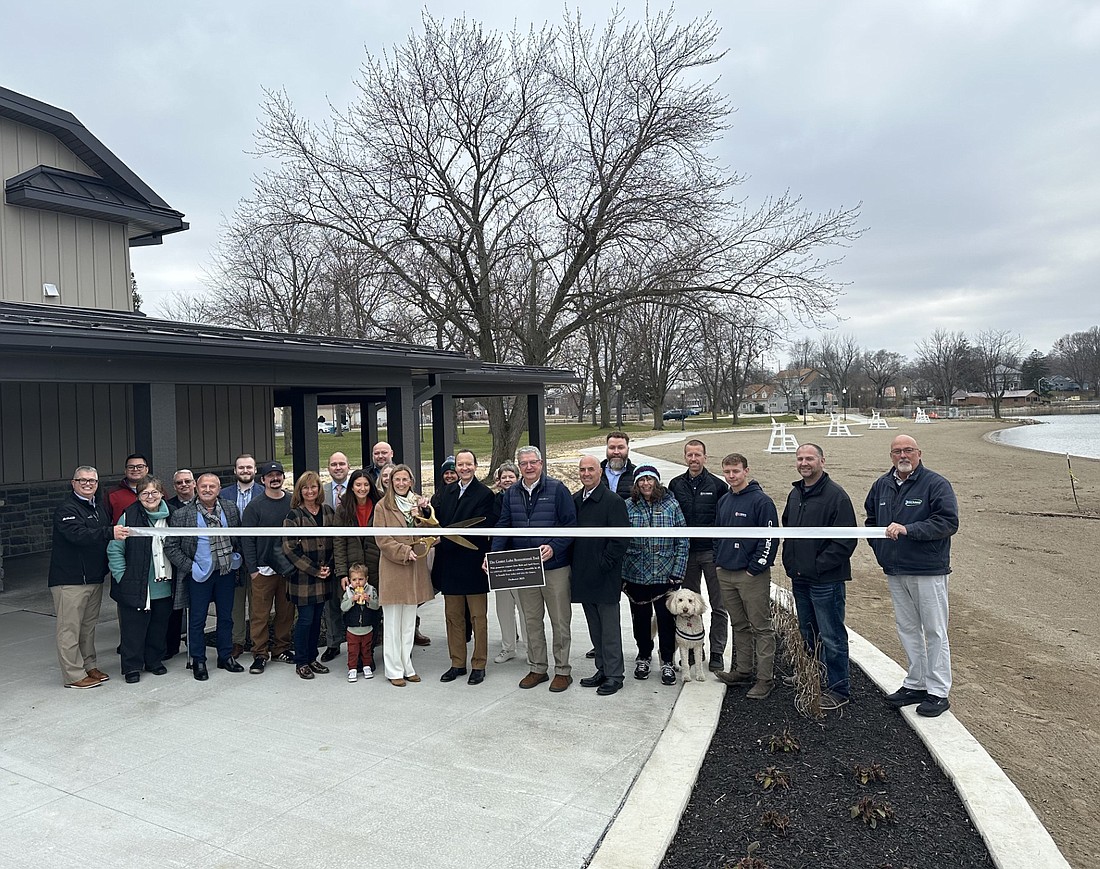 Rick and April Sasso (front, center, with scissors) cut the ribbon Monday for the Center Lake Recreational Trail during the ribbon-cutting ceremony with the Kosciusko Chamber of Commerce, K21 Health Foundation, city of Warsaw, A & Z Engineering, R. Yoder Construction and Warsaw Parks Board and staff. Photo by David Slone, Times-Union