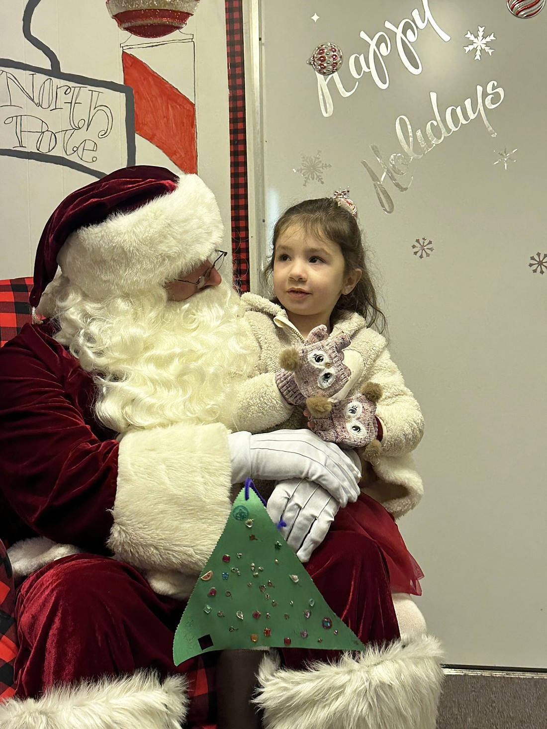 Evelyn Boldt tells Santa Claus what she wants for Christmas at the Warsaw Breakfast Optimist Club Santa’s House Friday night during Third Friday. She made the Christmas tree Santa is holding and gave it to him. Photo by David Slone, Times-Union