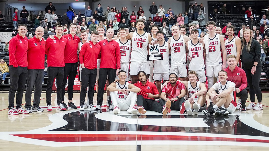 Grace's men's basketball team holding their 2024 Crossroads League regular season championship trophy. The Lancers cut the nets down after their final regular season game Saturday. Photo by Jeff Nycz