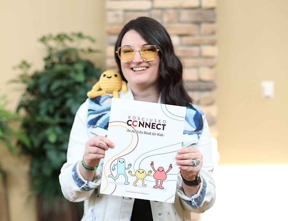 Haley Donahue holds the Kosciusko Connect activity book. On her shoulder sits a crocheted version of “Splice,” a character who appears in the activity book. Photo Provided