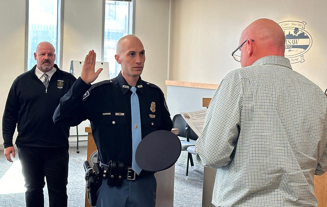 Warsaw Mayor Jeff Grose (R) gives Warsaw Police Department officer Cody Mangun (C) the ceremonial oath of office Monday as Mangun has completed his one-year probationary period with the department, with Police Chief (L) Scott Whitaker looking on. Photo by David Slone, Times-Union