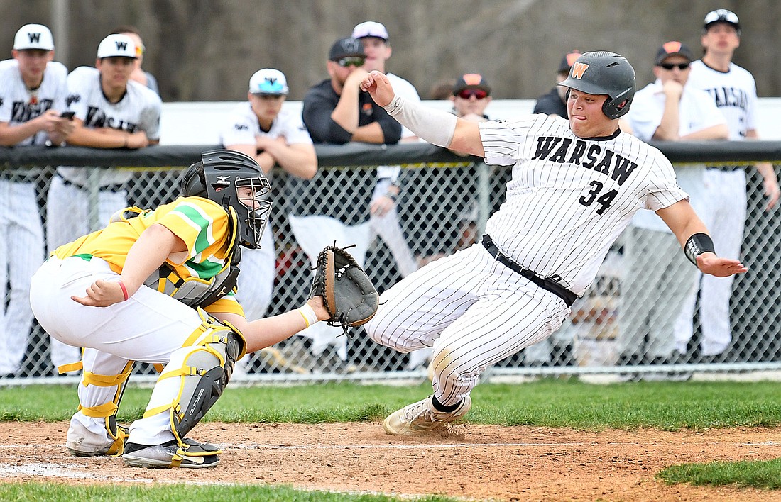 Tippecanoe Valley catcher Braxton Alderfer waits for the ball as Warsaw junior Hunter Dippon begins his slide to the plate to score Warsaw's first run during the second inning. Photo by Gary Nieter