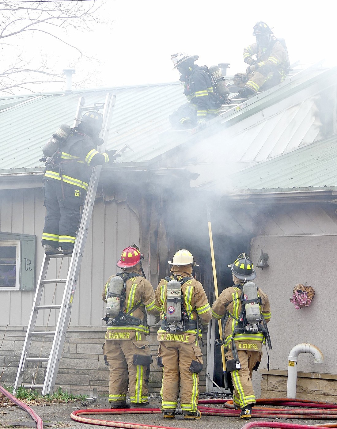 Crews work to get to the fire while on the roof. Photo by Gary Nieter, Times-Union