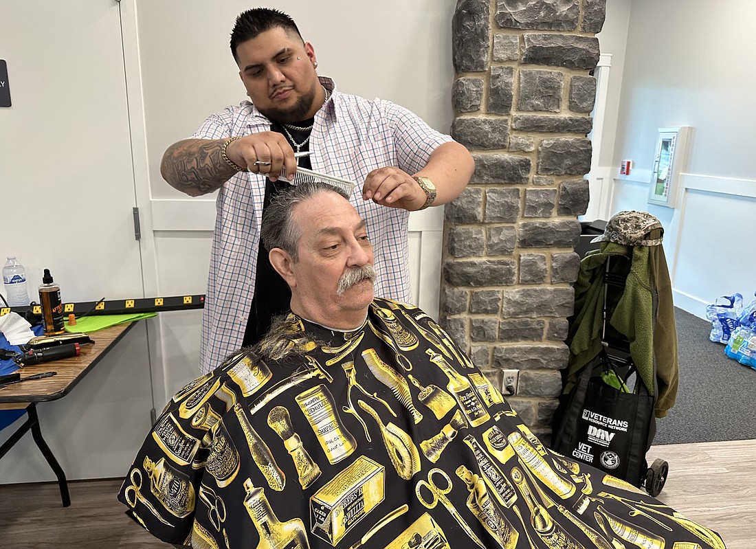 Emmanuel Arias, stylist with Shades N Fades, gives Terry Richards, of North Webster, a free haircut at the Veterans Stand Down Friday at the Zimmer Biomet Center Lake Pavilion. Photo by David Slone, Times-Union