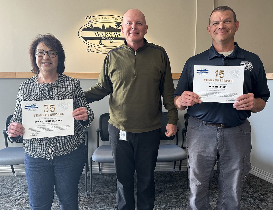 Two city of Warsaw employees were recognized Friday at the Board of Public Works and Safety meeting for their employment anniversaries. Jeff Helfers (R) has worked as a groundskeeper at Oakwood Cemetery for the past 15 years. Clerk-Treasurer Lynne Christiansen (L) marked 35 consecutive years of serving the city. Mayor Jeff Grose is pictured with the two employees. Photo by David Slone, Times-Union