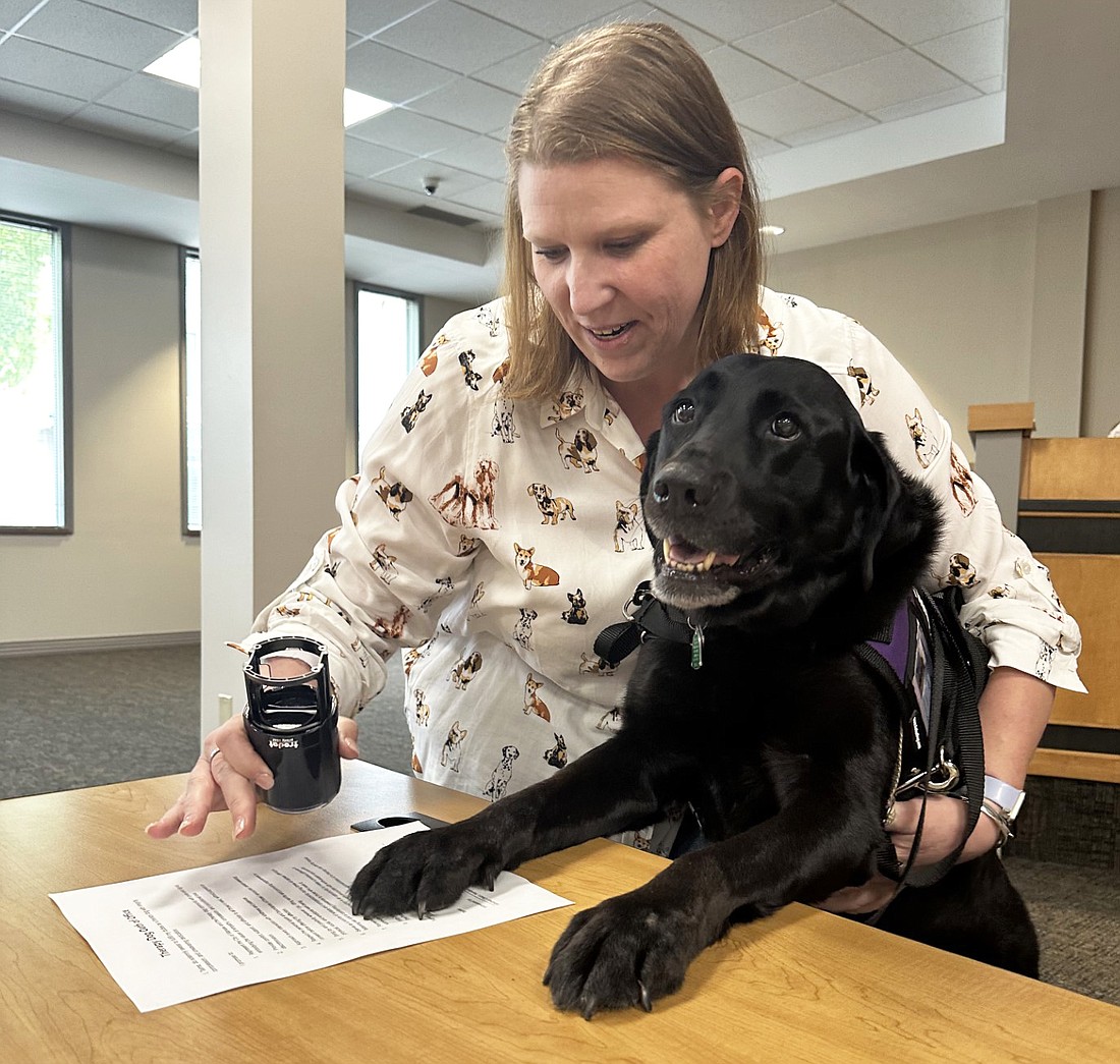 After taking the oath of office, Taima, the city of Warsaw’s therapy dog, signs the official paper with a paw print, assisted by handler and Mayor’s Office administrative assistant Whitney Olson. Photo by David Slone, Times-Union