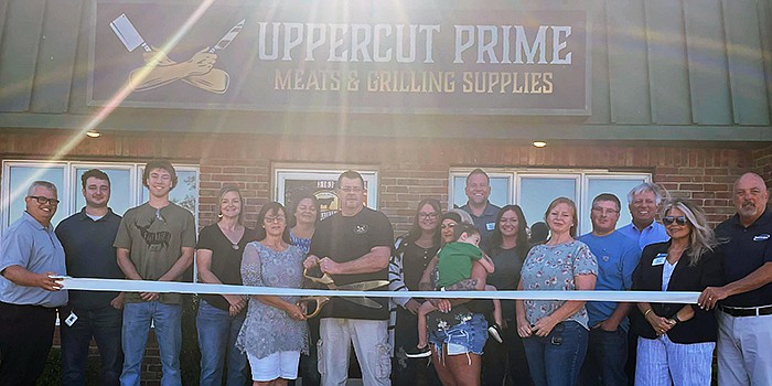 The Kosciusko Chamber of Commerce held a ribbon-cutting for Uppercut Prime Meats and Grilling Supplies in Warsaw on Friday. Pictured in the middle with the scissors are owners Tina and Steve Hughes. The Hughes' family and chamber ambassadors attended the ceremony. Photo by Liz Adkins, InkFreeNews