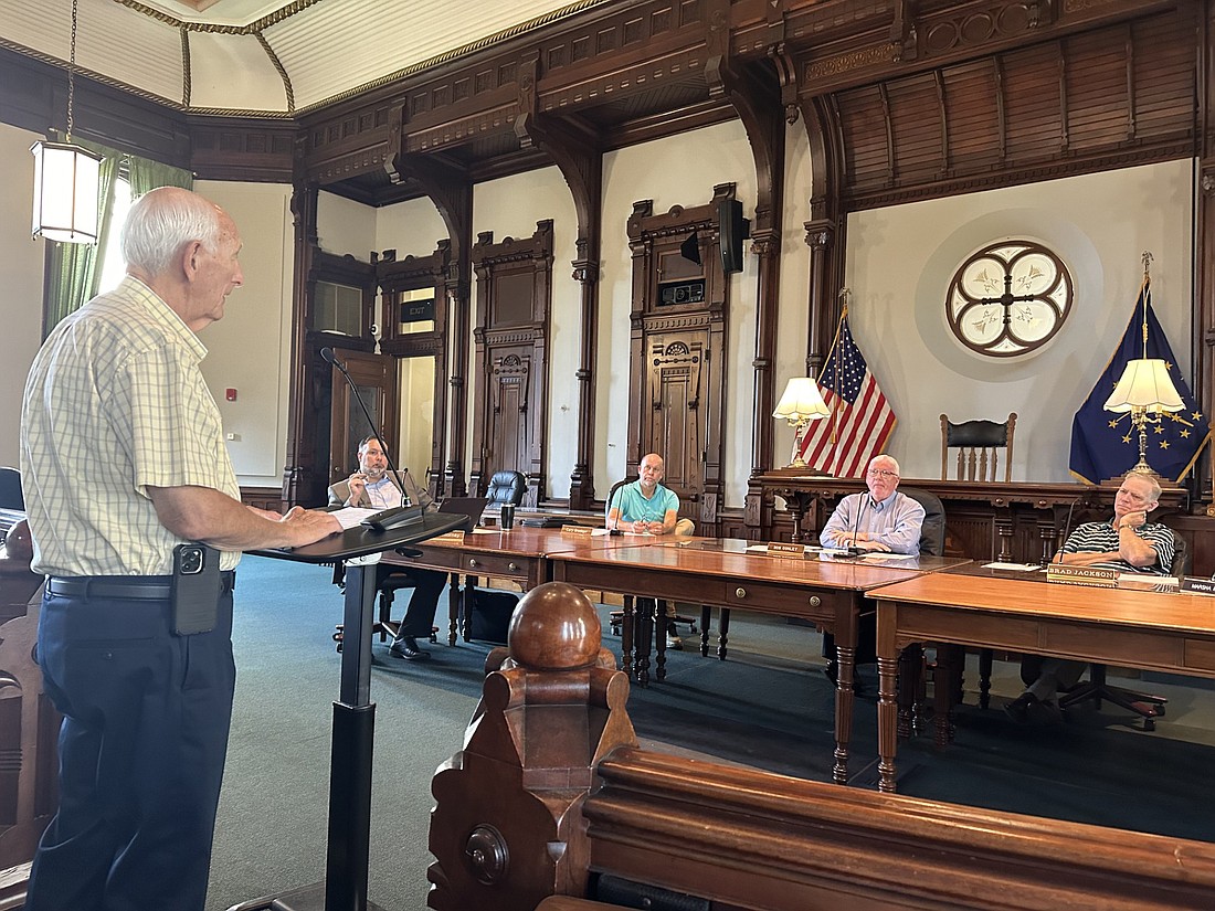 Mike Wyrick (L), president of the Webster Lake Conservation Association, speaks to the Kosciusko County Commissioners on Tuesday to request funding to help with the creation of the conservancy district. Pictured (L to R, seated) are county attorney Ed Ormsby and Commissioners Cary Groninger, Bob Conley and Brad Jackson. Photo by David Slone, Times-Union