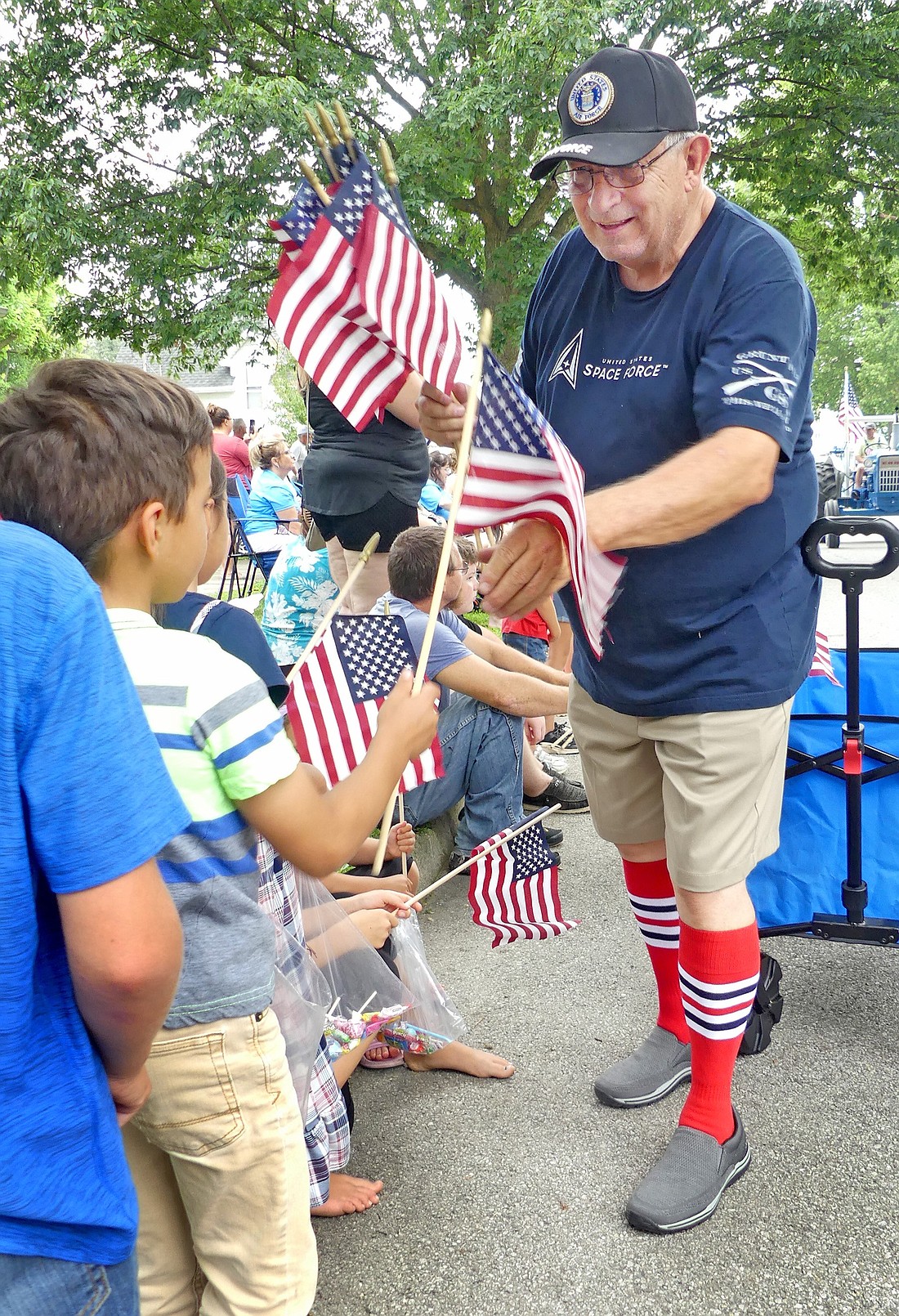 Larry Burkhart promotes the patriotic spirit of the day as he passes out flags along the parade route. Photo by Gary Nieter, Times-Union