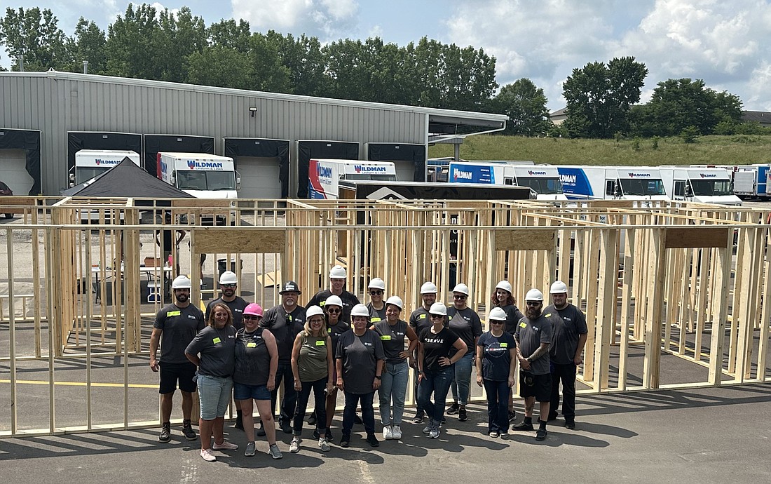 Wildman volunteers pose for a group photo in front of the frame for co-worker Kimber Boyd’s Habitat for Humanity home after the Panel Build at Wildman. Photo by David Slone, Times-Union