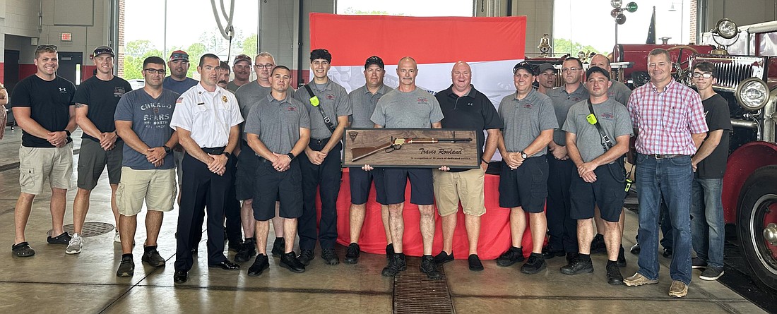 Warsaw-Wayne Fire Territory Lt. Travis Rowland (C) was presented with a gun and gun rack Friday at his retirement party. He is pictured with his fellow firefighters from the department. Photo by David Slone, Times-Union