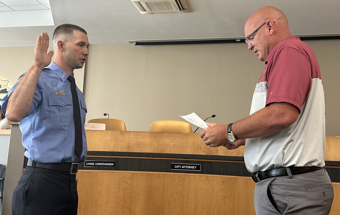 Warsaw Mayor Jeff Grose (R) gives Warsaw-Wayne Fire Territory firefighter Bryce Good (L) the oath of office Friday during the Warsaw Board of Public Works and Safety meeting as Good has completed his one-year probationary period. Photo by David Slone, Times-Union