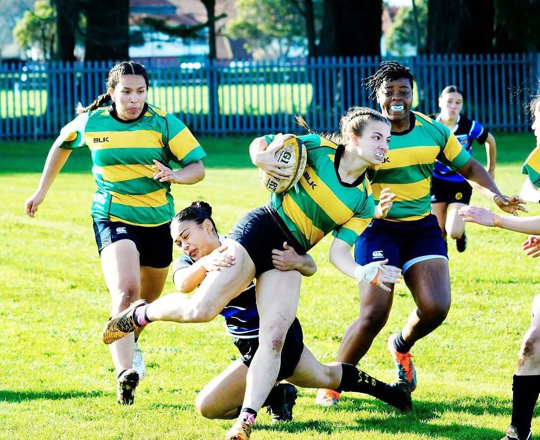 Recent Warsaw graduate Mia Blocher (center) breaks a tackle during a rugby game in New Zealand. Both Blocher and Raquel Muniz Bermudez (left) were selected to represent both their region and their country at an International Rugby Tour this summer.