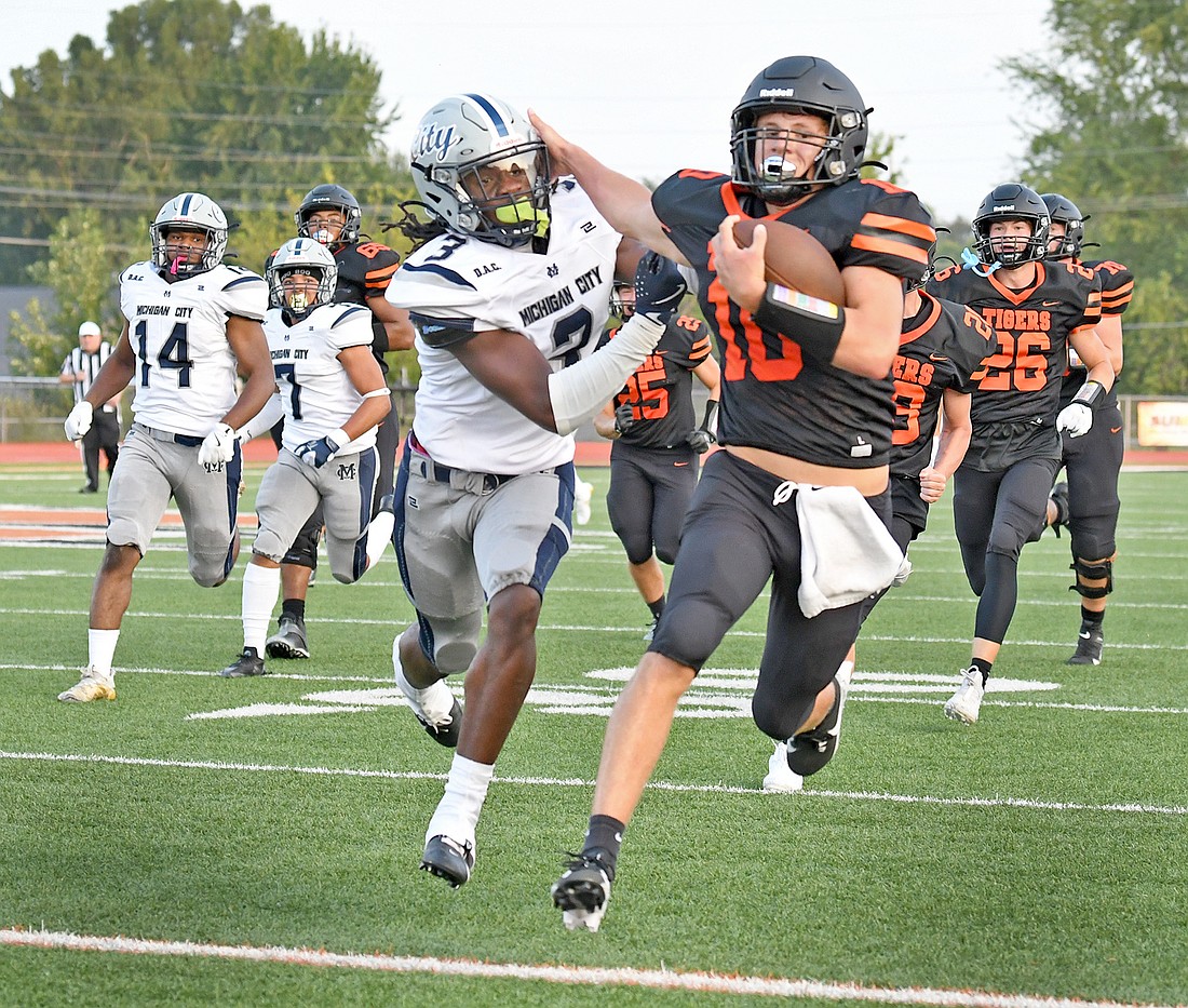 Warsaw junior Quinton Brock fights off a Michigan City defender while making a large gain in the first quarter to set up Warsaw's first touchdown of the night...Nieter