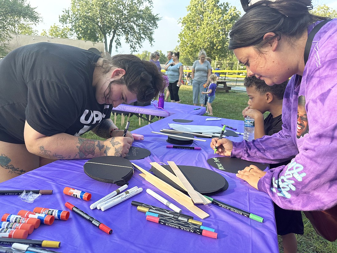 Allison Ceballos and Ashley Ferguson write the names of those they know who died from overdoses, including Ashley’s husband, Casey Ferguson III, and best friend’s brother, Keenan Creightney. Photo by David Slone, Times-Union