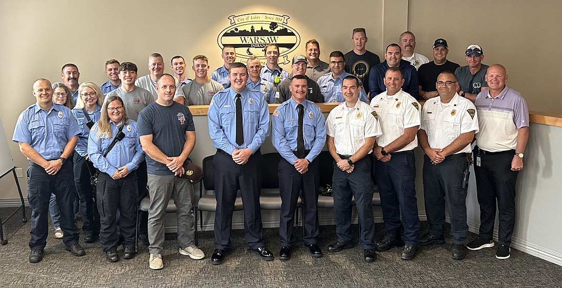 After taking their oaths of office, Warsaw-Wayne Fire Territory’s newest firefighters, Nicholas Cole (front row, fourth from left) and Cody Metzger (front row, fifth from right) pose for a group photo with the department’s other firefighters and Mayor Jeff Grose (front row, far right). Photo by David Slone, Times-Union