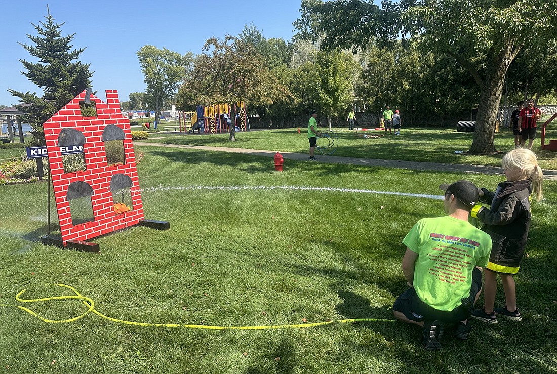 Warsaw-Wayne Fire Territory Bryce Good helps 7-year-old Reagan Wilson with the fire hose Saturday during Family Safety Day. Photo by David Slone, Times-Union