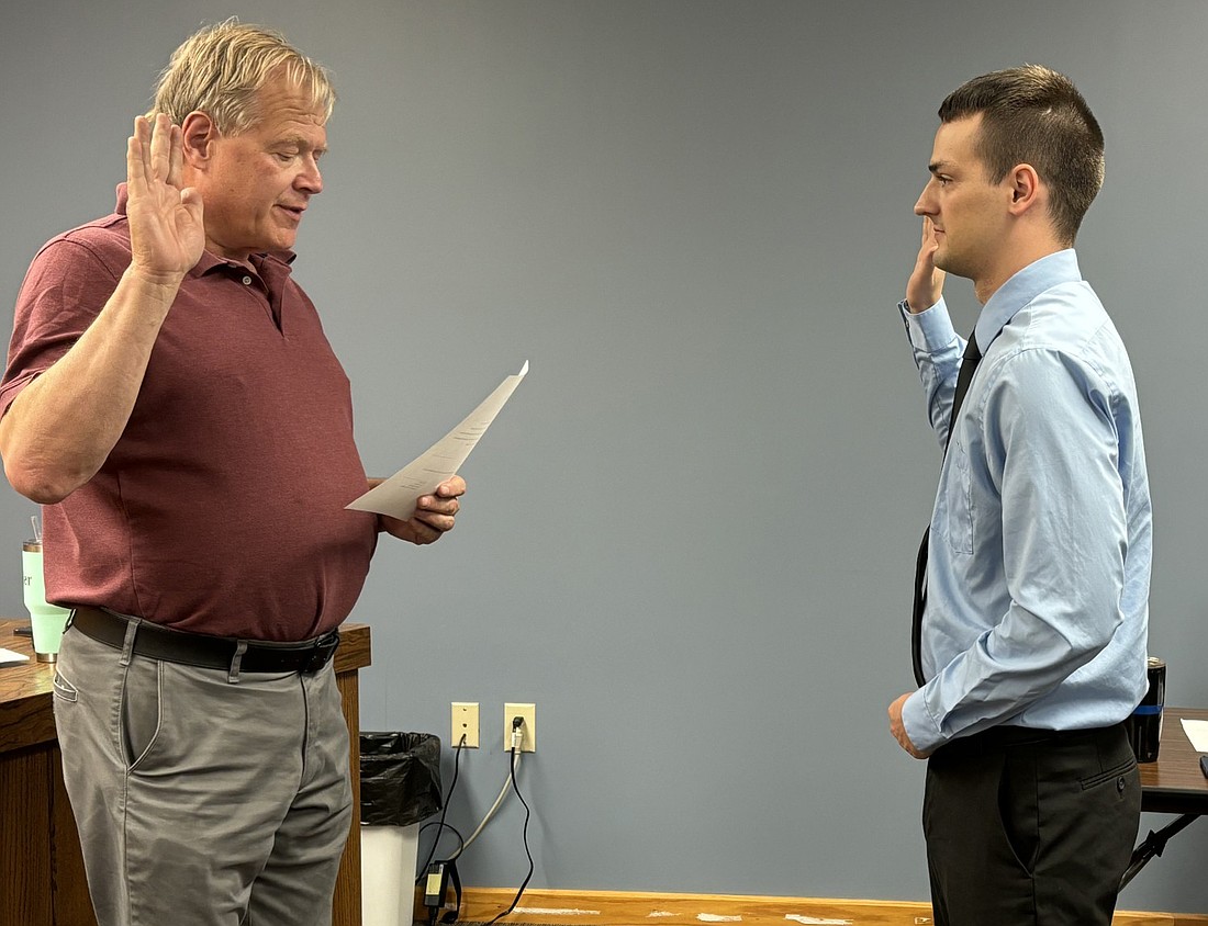 Syracuse town attorney Jay Rigdon (L) swears in new police officer Jacob Bolen at the town council meeting Tuesday evening. Photo by Denise Fedorow