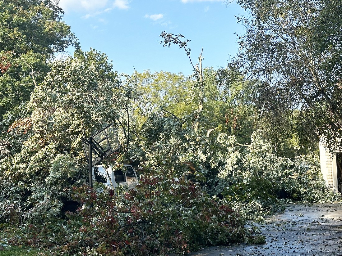 A van and a basketball hoop are barely visible after a tree came down on them from Friday’s microburst on Blue Heron Drive in Valley Springs subdivision, Warsaw. Photo by David Slone, Times-Union