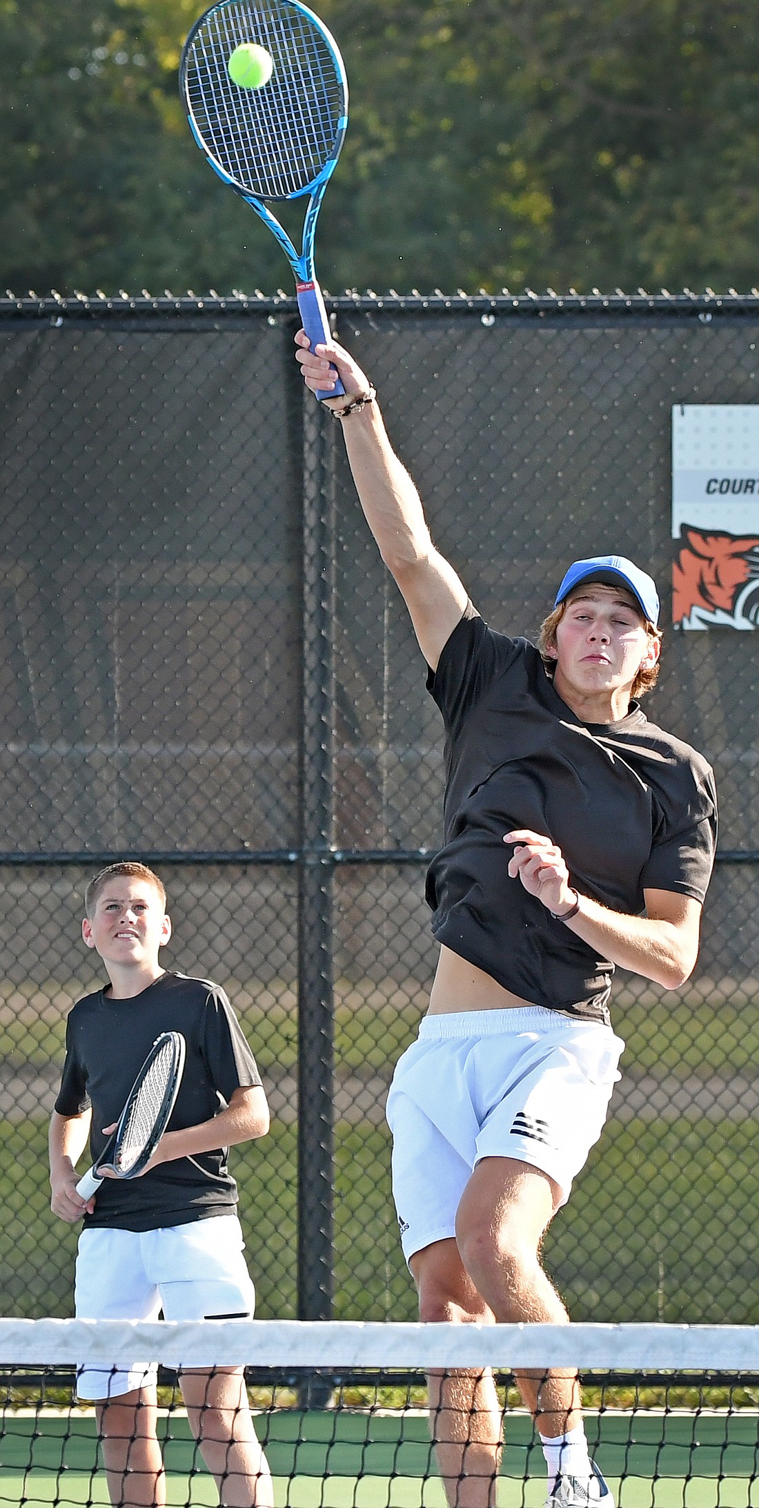 Warsaw's lone senior Drew Ryser reaches for an overhead return as partner Henry Norton looks on during their No. 1 doubles match against Whitko...Nieter