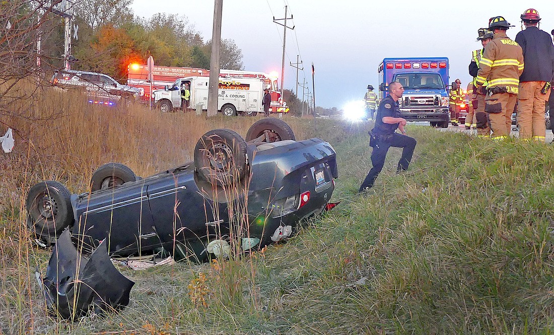 One of the vehicles involved in Friday morning's collision on U.S. 30 at CR 325E lays in a ditch east of the intersection. The driver of the other vehicle is checked out by medics in the background. Photo by Gary Nieter, Times-Union.