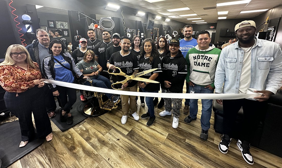 Jeffrey Ortega (center, with scissors) cuts the ribbon for his business, Shaves & Fades, 2128 E. Winona Ave., Warsaw, during the ribbon-cutting ceremony Thursday with the Kosciusko Chamber of Commerce. Photo by David Slone, Times-Union