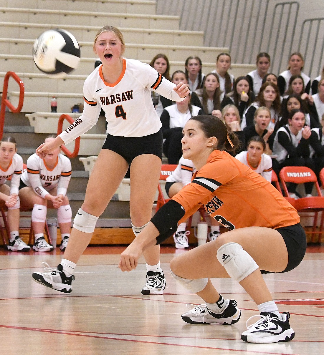 Junior Ellie Hepler goes low for a dig while classmate Cece Goode shouts encouragement from behind...Nieter