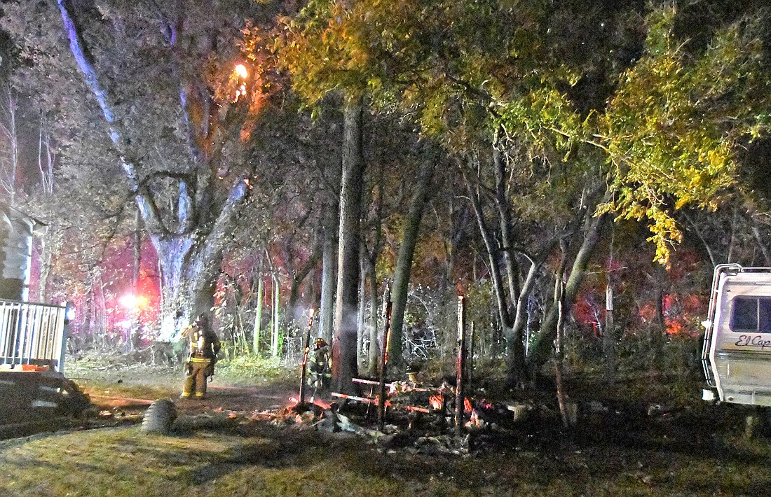 Firefighters turn their attention to a tree fire after extinguishing a fire in the backyard of a residence west of CR 700E on Old 30 late Tuesday night. Photo by Gary Nieter, Times-Union