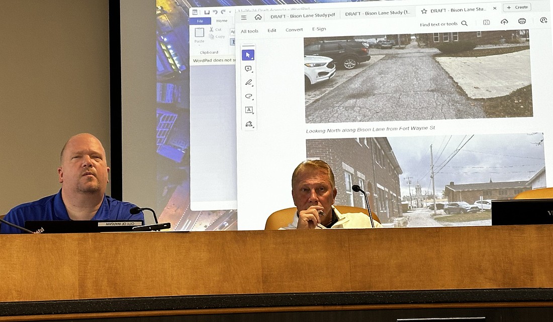 Warsaw Police Department Capt. Joel Beam (L) and Warsaw Traffic Administrator Lance Grubbs (R) look at some photos of the Bison Lane and east-west alley during Wednesday’s Warsaw Traffic Commission meeting. Photo by David Slone, Times-Union