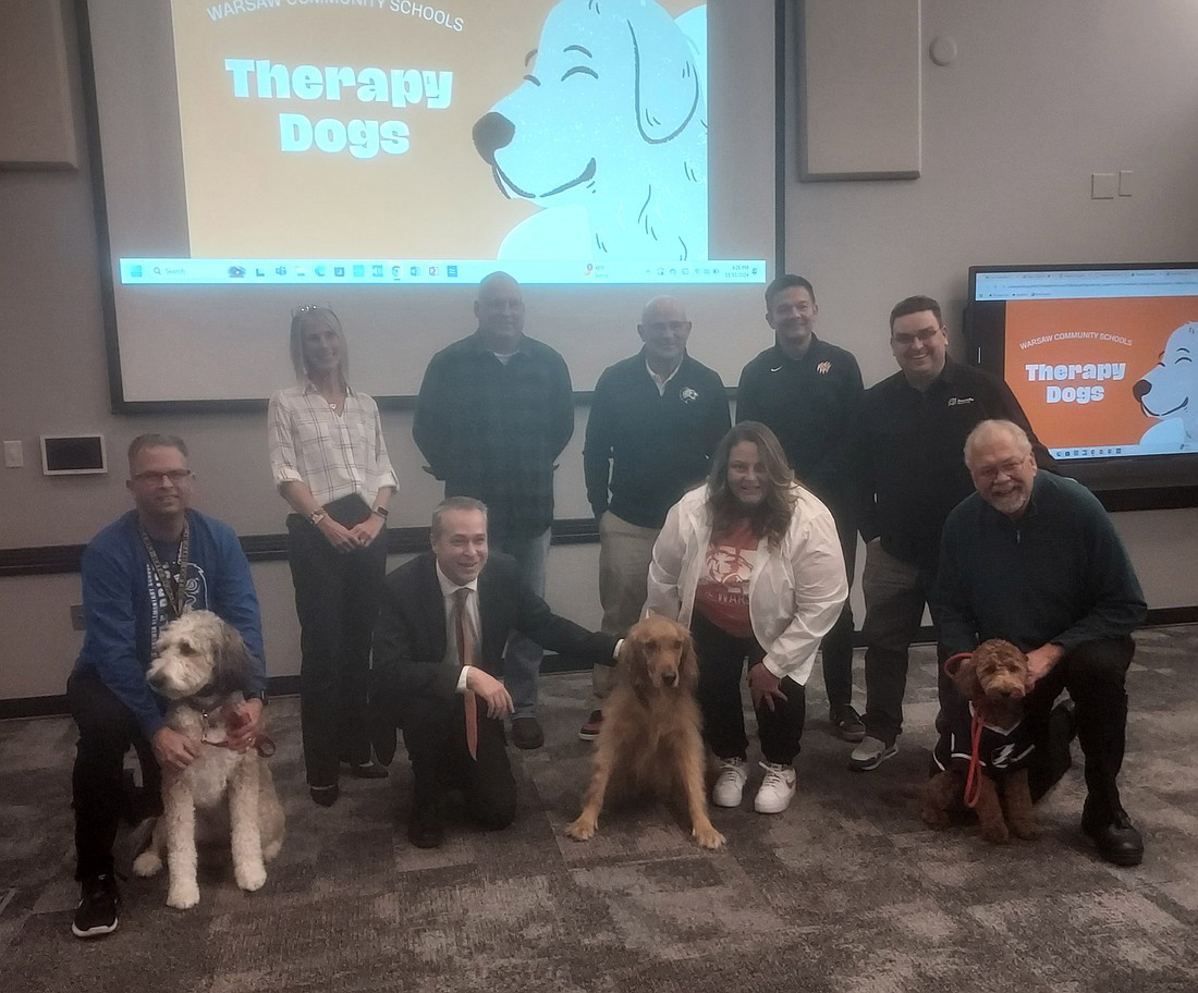 Pictured are the members of the Warsaw School Board, Superintendent Dr. David Hoffert; Andy Streit, physical education teacher at Eisenhower; Dena Lancaster, family and consumer sciences teacher at WACC; and therapy dogs Champ, Maya and Sawyer. Photo by Jackie Gorski, Times-Union