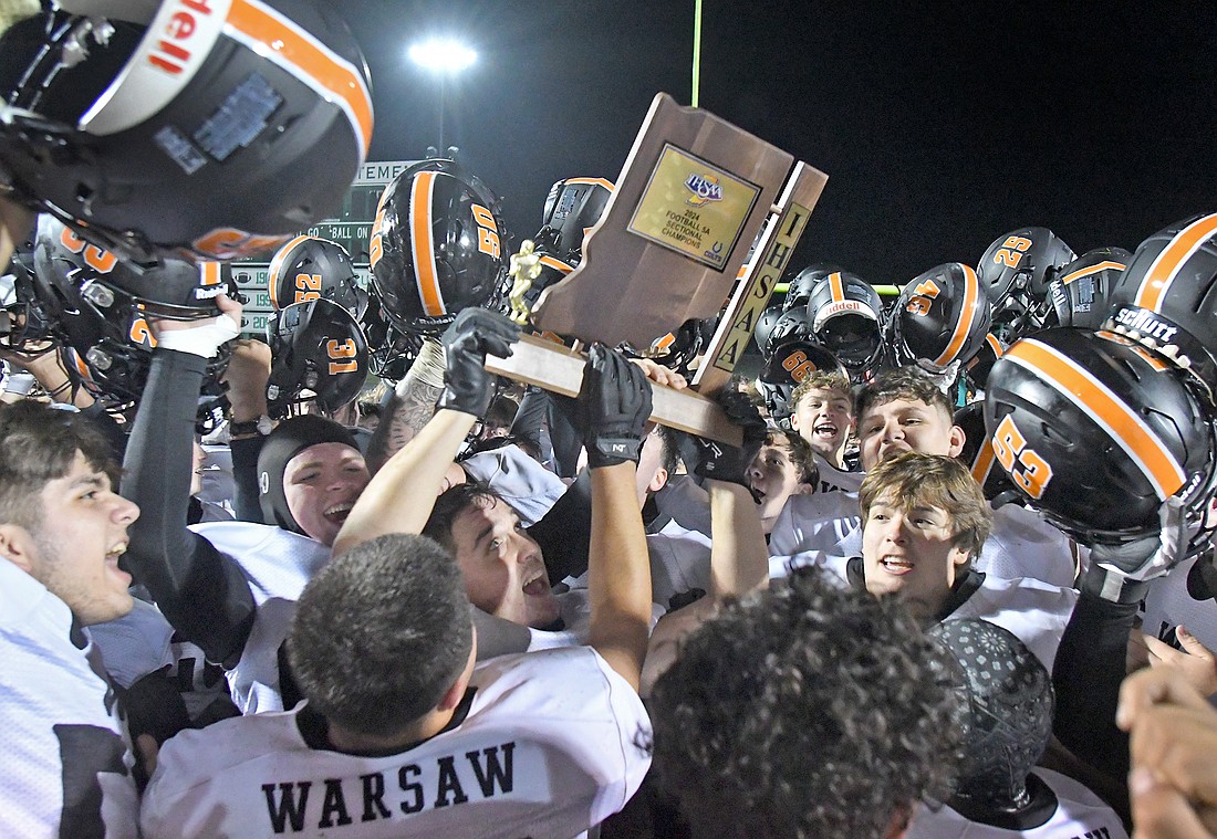 The Warsaw football team hoists a sectional trophy after defeating No. 1 Concord 31-28 Friday night in the IHSAA 5A Sectional 11